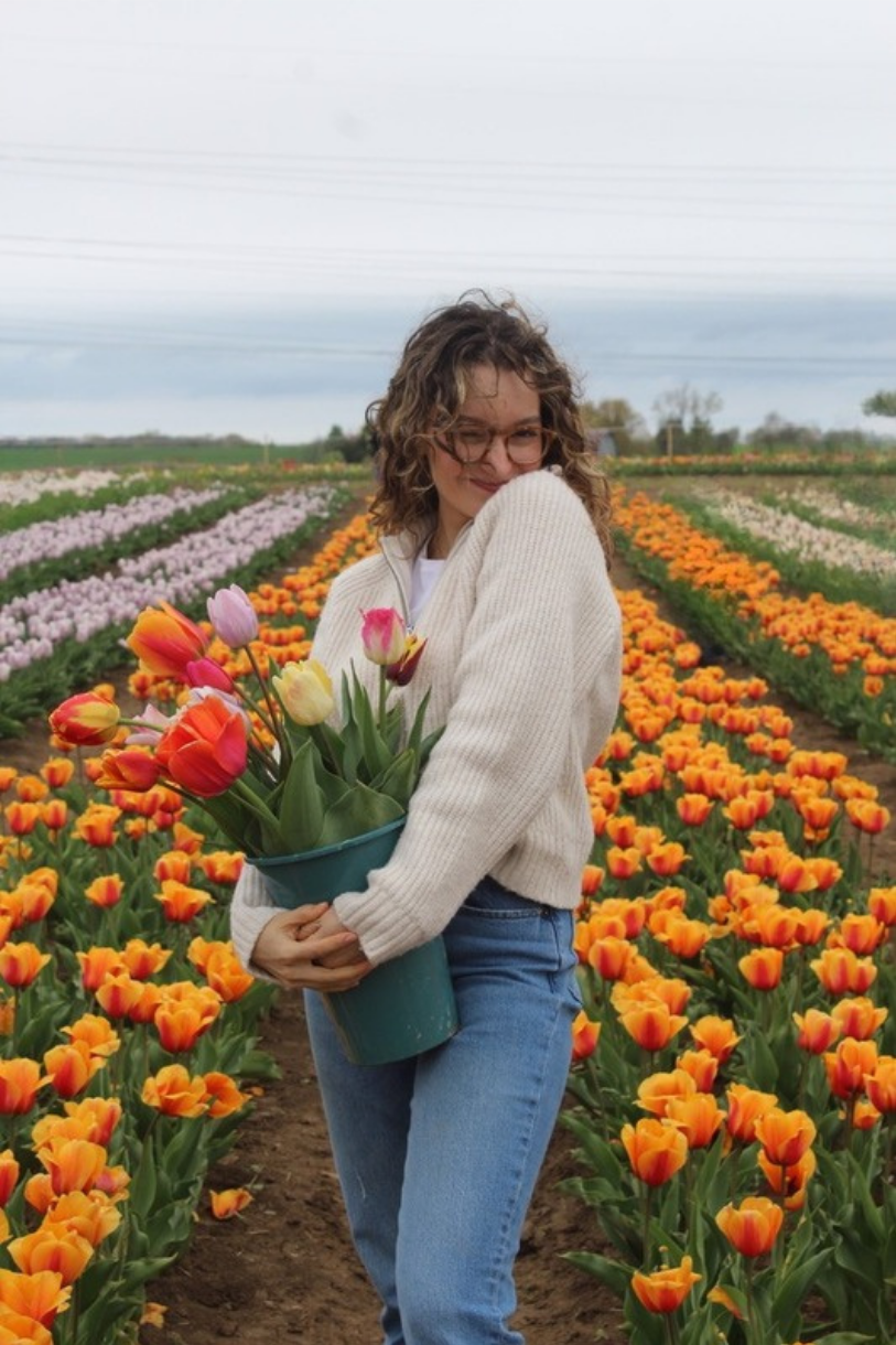 Carolina holding a bucket of tulips in a tulip field