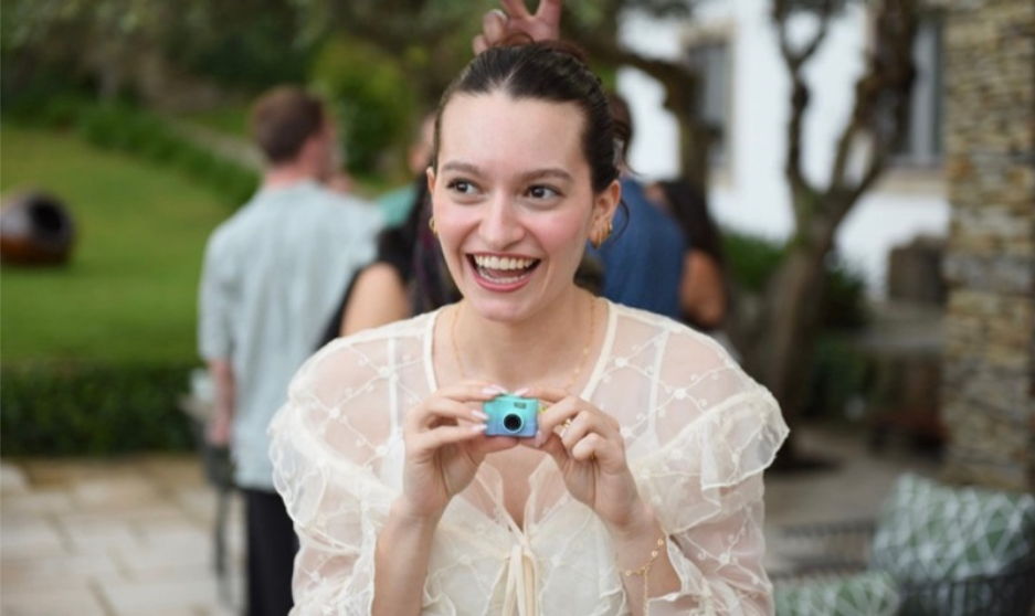Carolina, maker behind Paper & Pixel, smiling with a little blue camera